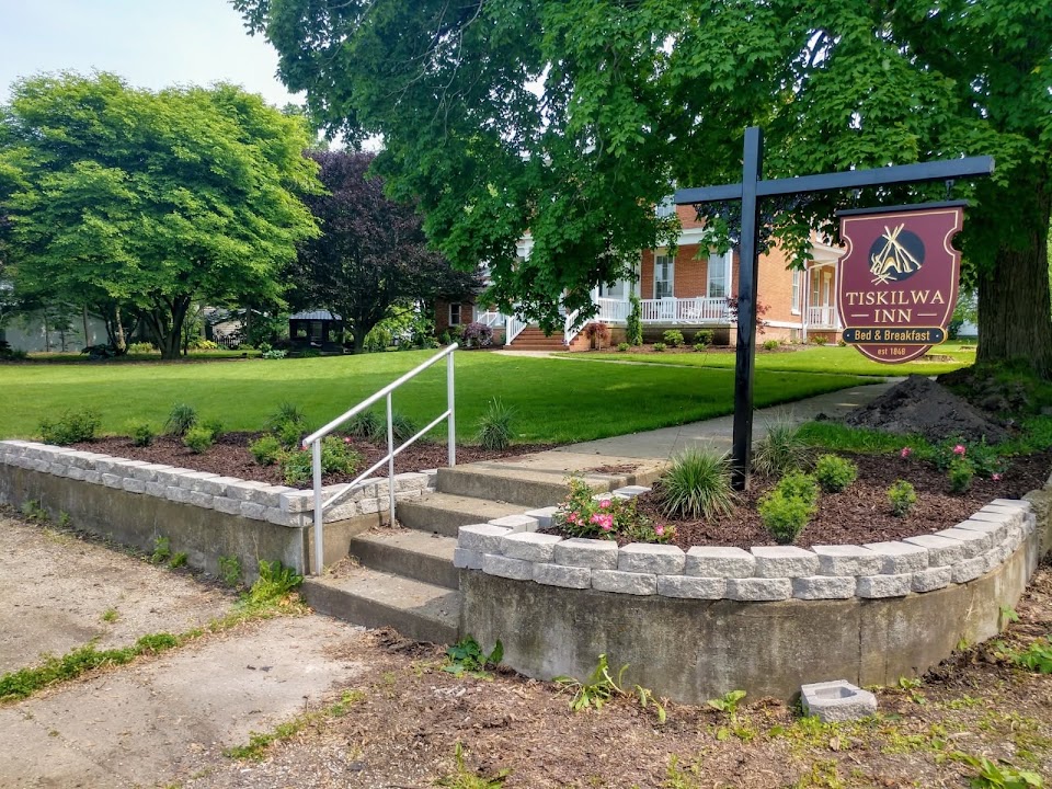 The Tiskilwa Inn sign and stone steps among leafy trees